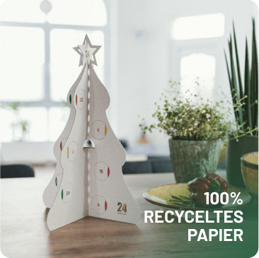 Weißer 24guteTaten Adventskalender in Tannenbaumform aus 100 % recyceltem Papier auf einem Holztisch.